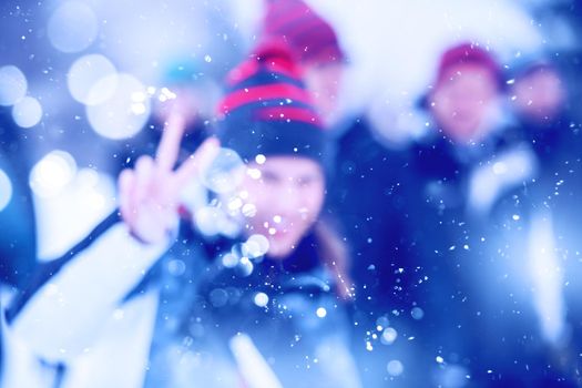 Abstract blurred photo of young happy woman with her business team enjoying snowy winter day while snowflakes flying around them during a team building in the mountain forest