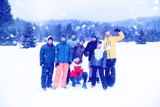 group portrait of young happy business people enjoying snowy winter day with snowflakes around them during a team building in the mountain forest