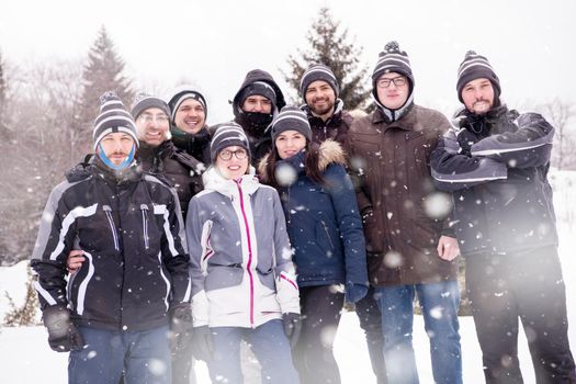 group portrait of young happy business people enjoying snowy winter day with snowflakes around them during a team building in the mountain forest