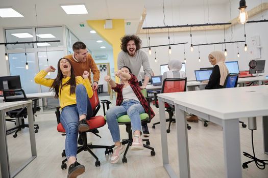 business people having fun while racing on office chairs