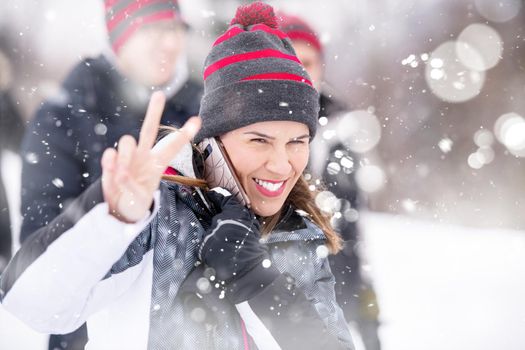 portrait of young happy woman with her business team enjoying snowy winter day while snowflakes flying around them during a team building in the mountain forest