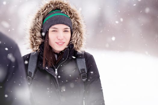 Woman in winter season  Portrait of young woman in warm clothes enjoying snowy day with snowflakes around her in the winter forest