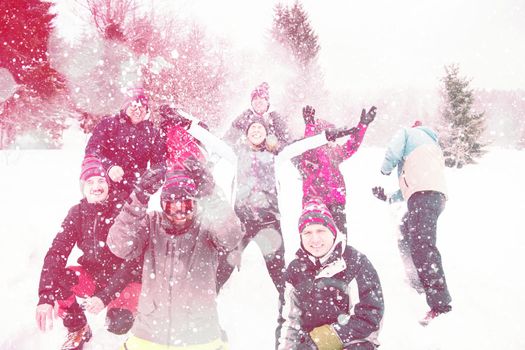 group of young happy business people having fun throwing snow in the air while enjoying snowy winter day with snowflakes around them during a team building in the mountain forest