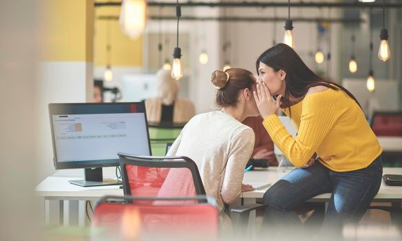 office rumors with two girls whispering in  coworking  open space startup business office