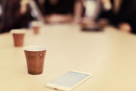 startup business team on meeting in modern bright office interior brainstorming, working on laptop and tablet computer. Smartphone on table in focus