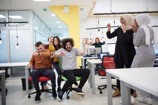 business people having fun while racing on office chairs