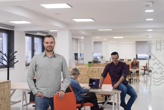 portrait of young businessman in casual clothes at modern  startup business office space,  team of people working together in background