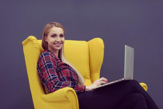 startup business, woman  working on laptop computer at modern office and sitting on creative yellow armchair