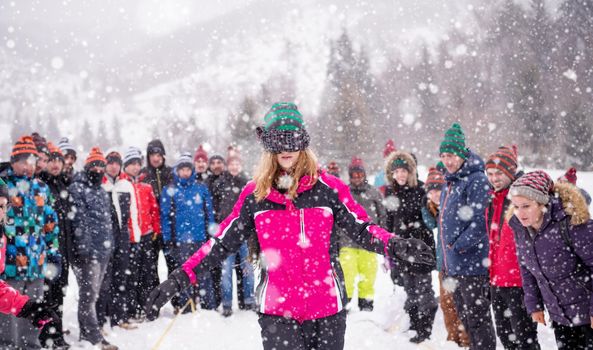 group of young happy business people having a Blindfolded games competition while enjoying snowy winter day with snowflakes around them during a team building in the mountain forest