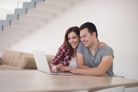 happy young couple buying online using laptop a computer and a credit card in their luxury home villa