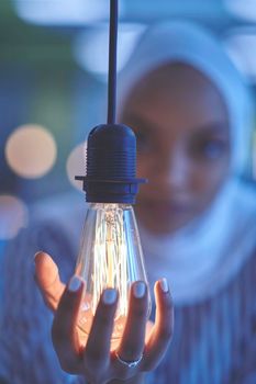 internet of things concept woman holding hands around bulb smart saving energy wearing hijab as traditional muslim