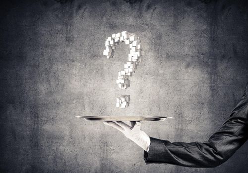 Cropped image of waitress hand in white glove presenting multiple cubes in form of question mark on metal tray with dark wall on background