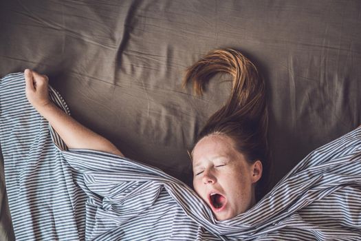 Beautiful young woman lying down in bed and sleeping, top view. Do not get enough sleep concept.