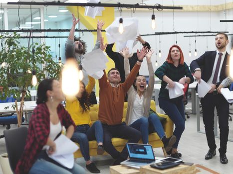 Group of business people having party and  throwing paper in air at modern coworking open space  startup office