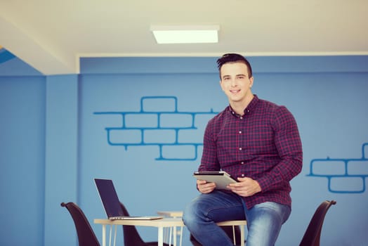 portrait of young business man in casual clothes sitting on table at  new startup office space