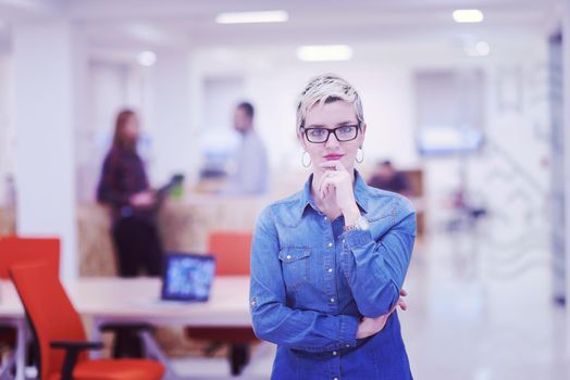 portrait of young business woman at modern startup office interior, team in meeting in background