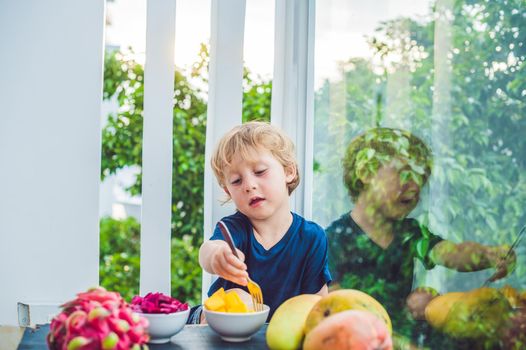 Little cute boy eating mango on the terrace.