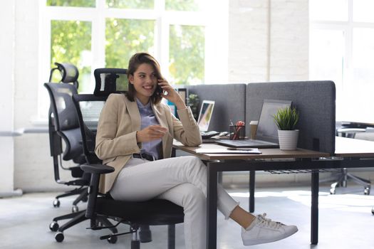 Young smiling business woman using smartphone in office