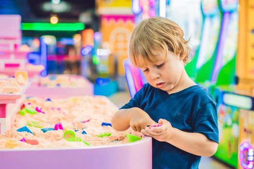 Boy playing with kinetic sand in preschool. The development of fine motor concept. Creativity Game concept.