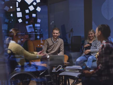 Disabled businesswoman in a wheelchair having a meeting with the diverse business people team at modern startup open space office 