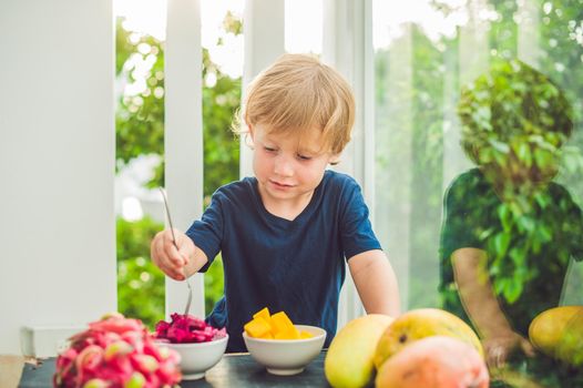 Little cute boy eating mango on the terrace.