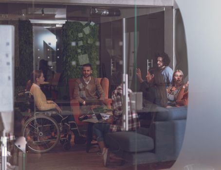 Disabled businesswoman in a wheelchair having a meeting with the diverse business people team at modern startup open space office 