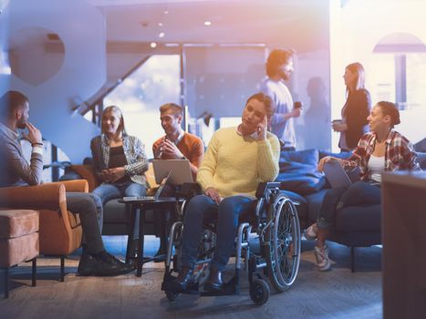 Portrait of disabled businesswoman in a wheelchair in front of her diverse business team in a modern open space coworking office space. High quality photo