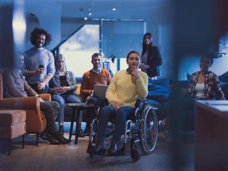 Portrait of disabled businesswoman in a wheelchair in front of her diverse business team in a modern open space coworking office space. High quality photo