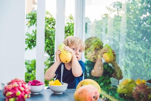 Little cute boy eating mango on the terrace.