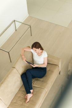 young happy woman on sofa using tablet computer at luxury home