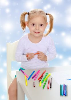 Pretty little blonde girl drawing with markers at the table.Girl holding in hands blue marker.The concept of celebrating the New year, Holy Christmas, or child's birthday on a blue background
