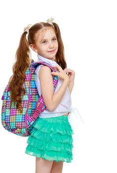 Cute little girl with long hair to the waist which wire braided white ribbons. In a white shirt without a pattern and green short skirt. The girl holds the shoulders schoolbag. Close-up - Isolated