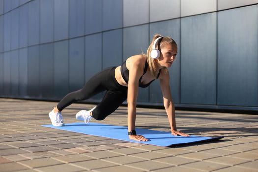 Athletic determined slim woman doing exercises on the blue mat outdoor