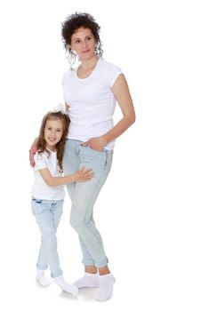 Mom and daughter in matching jeans and white shirts do fitness - Isolated on white background