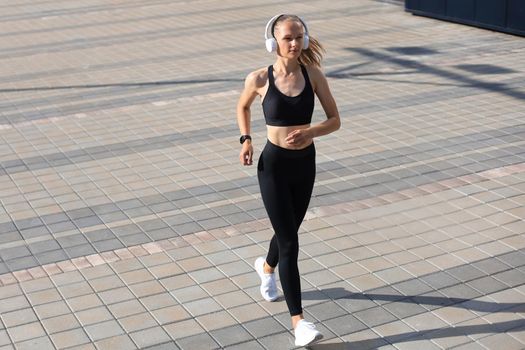 Young attractive woman with perfect slim body running outdoors. Fitness and running concept