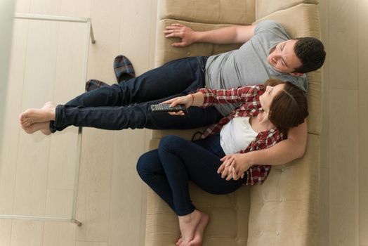 Young couple on the sofa watching television together in their luxury home