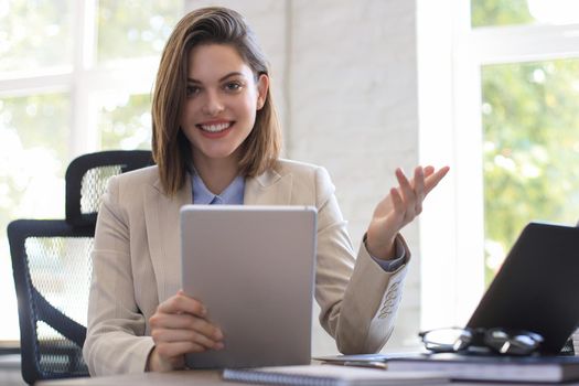 Attractive smiling woman working on a tablet in modern office