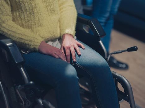 Sad and depressed disabled businesswoman in a wheelchair at the office with coworkers. Diverse business team in a modern open space coworking office space. High quality photo