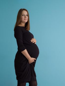 Portrait of happy pregnant woman with hands on belly isolated over blue background