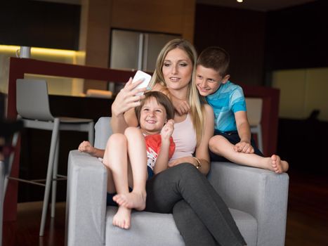 Happy family siting on sofa and using cell phone for video call  at home