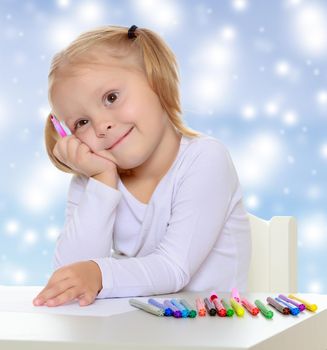 Pretty little blonde girl drawing with markers at the table.Girl put head on his hand , she dreams about something.The concept of celebrating the New year, Holy Christmas