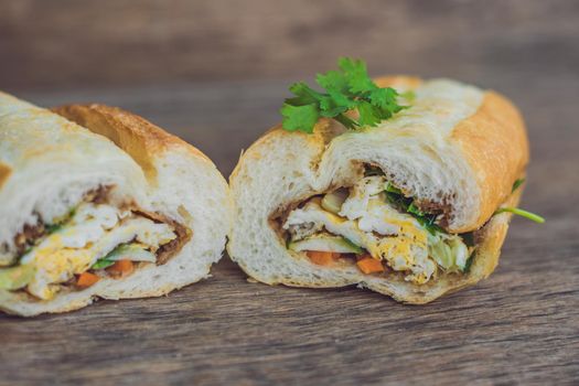 A delicious Vietnamese Bahn Mi sandwich on a wooden background.