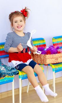 Happy little girl sitting on a chair . Next to it lay a box with new clothes in which she will dress up.
