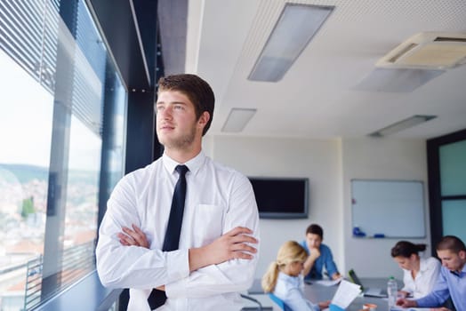 Portrait of a handsome young  business man  on a meeting in offce with colleagues in background