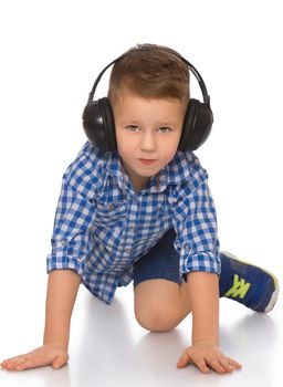 Music little boy listens through the large black headphones music. He crawls on the floor - Isolated on white background
