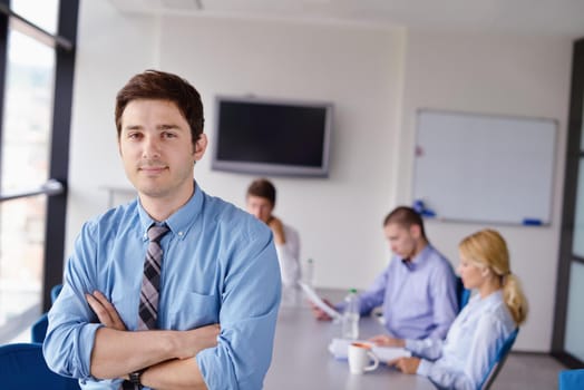 Portrait of a handsome young  business man  on a meeting in offce with colleagues in background