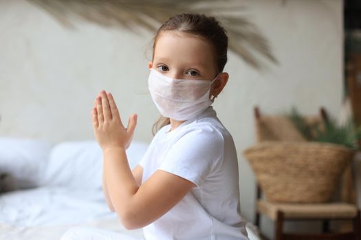 Little girl wearing mask for protect Covid-19. She praying in the morning for a new day freedom to world corona virus. Little girl hand praying for thank GOD.