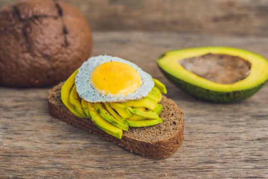 Toast with avocado and egg on rustic wooden background.