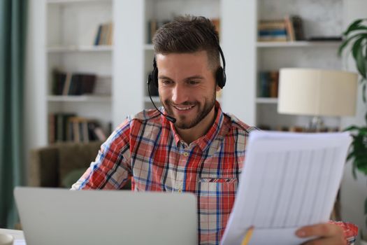 Concentrated young freelancer businessman using laptop for video conferance, working remotely online at home