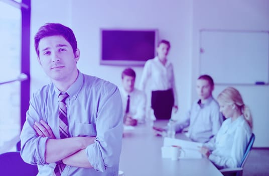 Portrait of a handsome young  business man  on a meeting in offce with colleagues in background